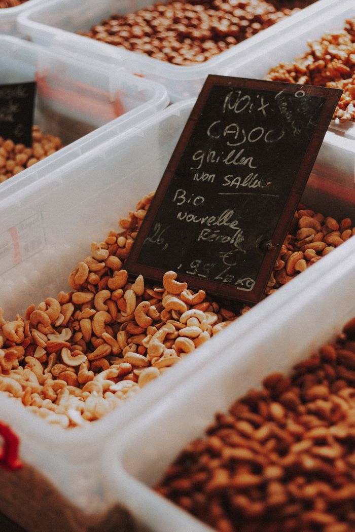 Close-up of organic cashew nuts in plastic containers with a chalkboard sign at a market.
